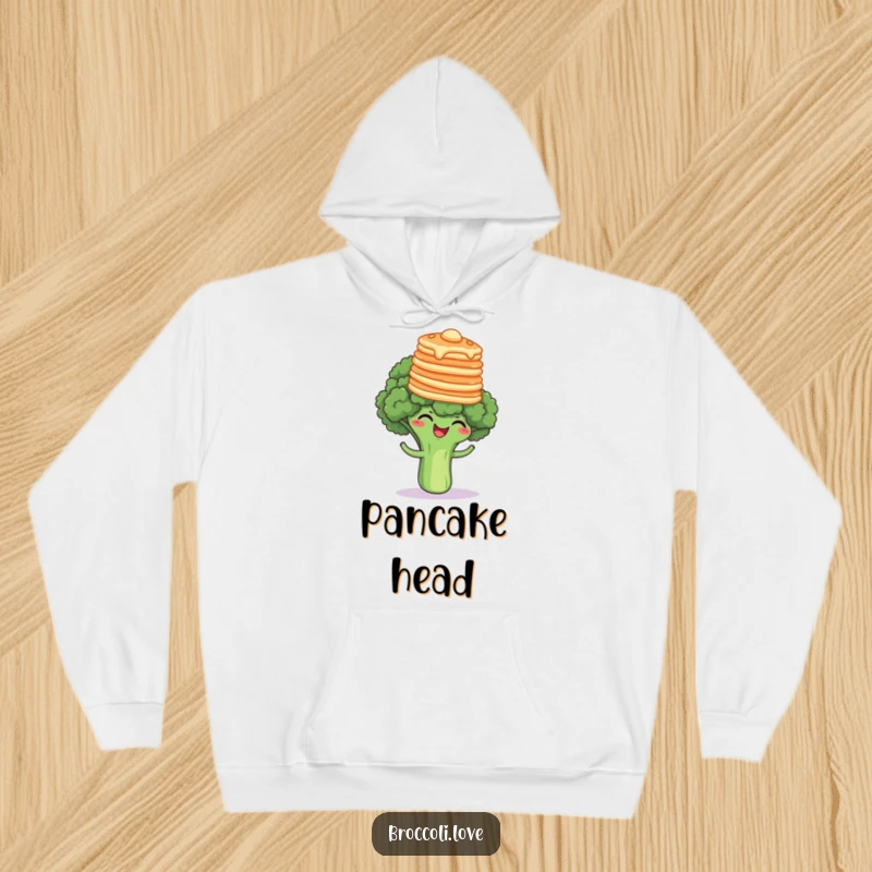 Funny broccoli floret giggling with a stack of pancakes on its head, a warm and humorous hoodie design for breakfast enthusiasts.